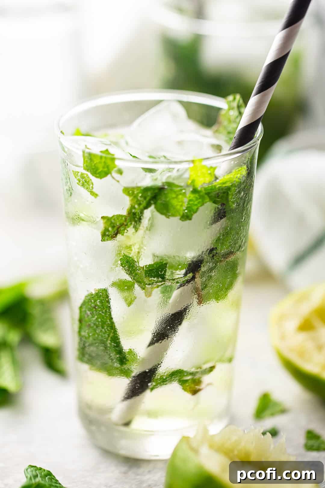 A close-up view of impeccably presented mojitos in clear highball glasses, adorned with fresh mint leaves and halved limes, evoking a sense of vibrant freshness.