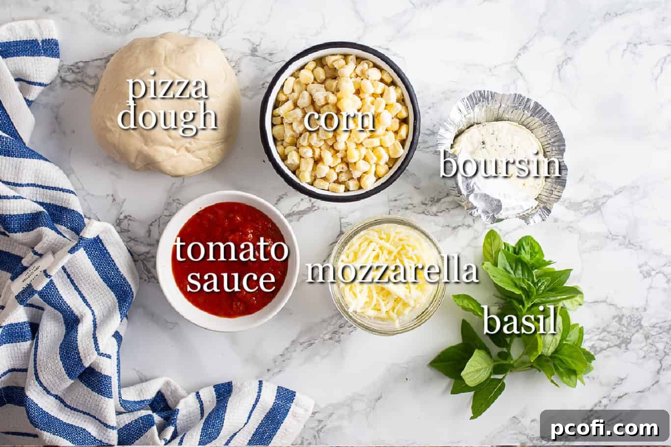 Various fresh ingredients laid out for making corn pizza, including pizza dough, a bowl of tomato sauce, mozzarella cheese, corn kernels, a block of Boursin cheese, and fresh basil leaves, each with a clear label.