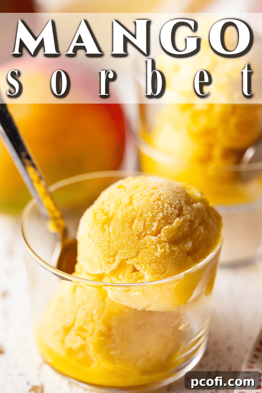 A small glass dish filled with vibrant mango sorbet, ready to be enjoyed, with a blurred background.