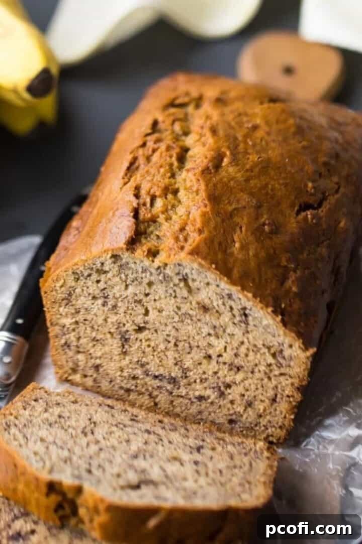 loaf of banana bread with a few slices on a wooden cutting board.