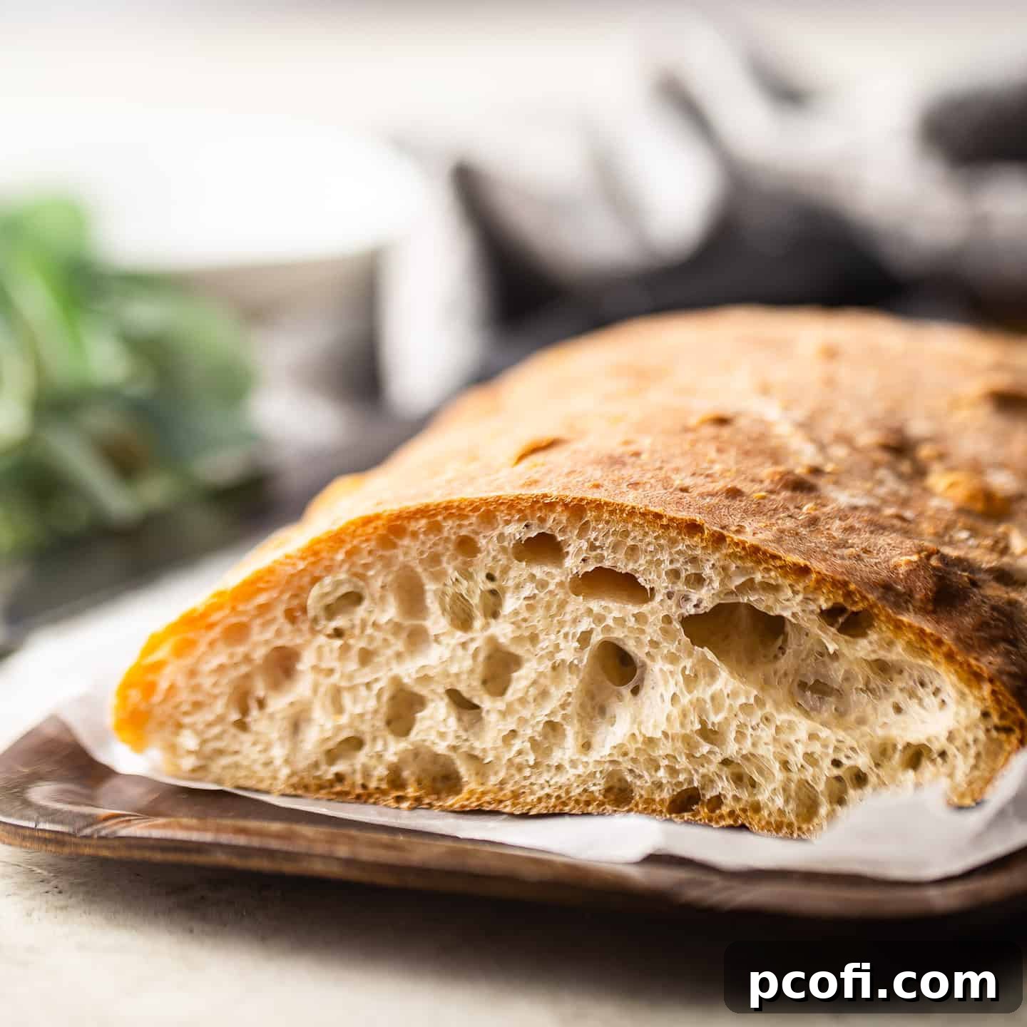A close-up image of a sliced ciabatta loaf, revealing its characteristic light, airy interior with large, irregular holes.