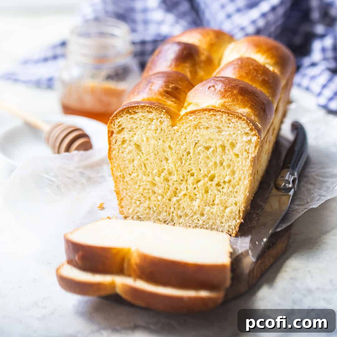 A golden-brown brioche loaf resting on a wooden board, with a charming blue checked cloth in the background.