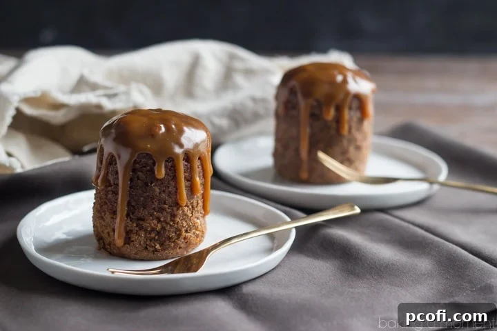 Close-up of a single serving of Dark and Stormy Sticky Toffee Pudding, showing the moist cake and generous pour of butter rum sauce, making it an irresistible and comforting dessert.