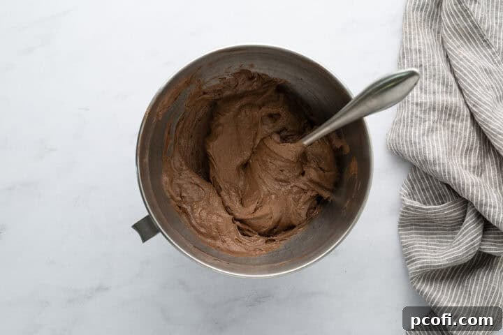 Smooth chocolate cupcake batter in a large mixing bowl with a spatula, ready for baking