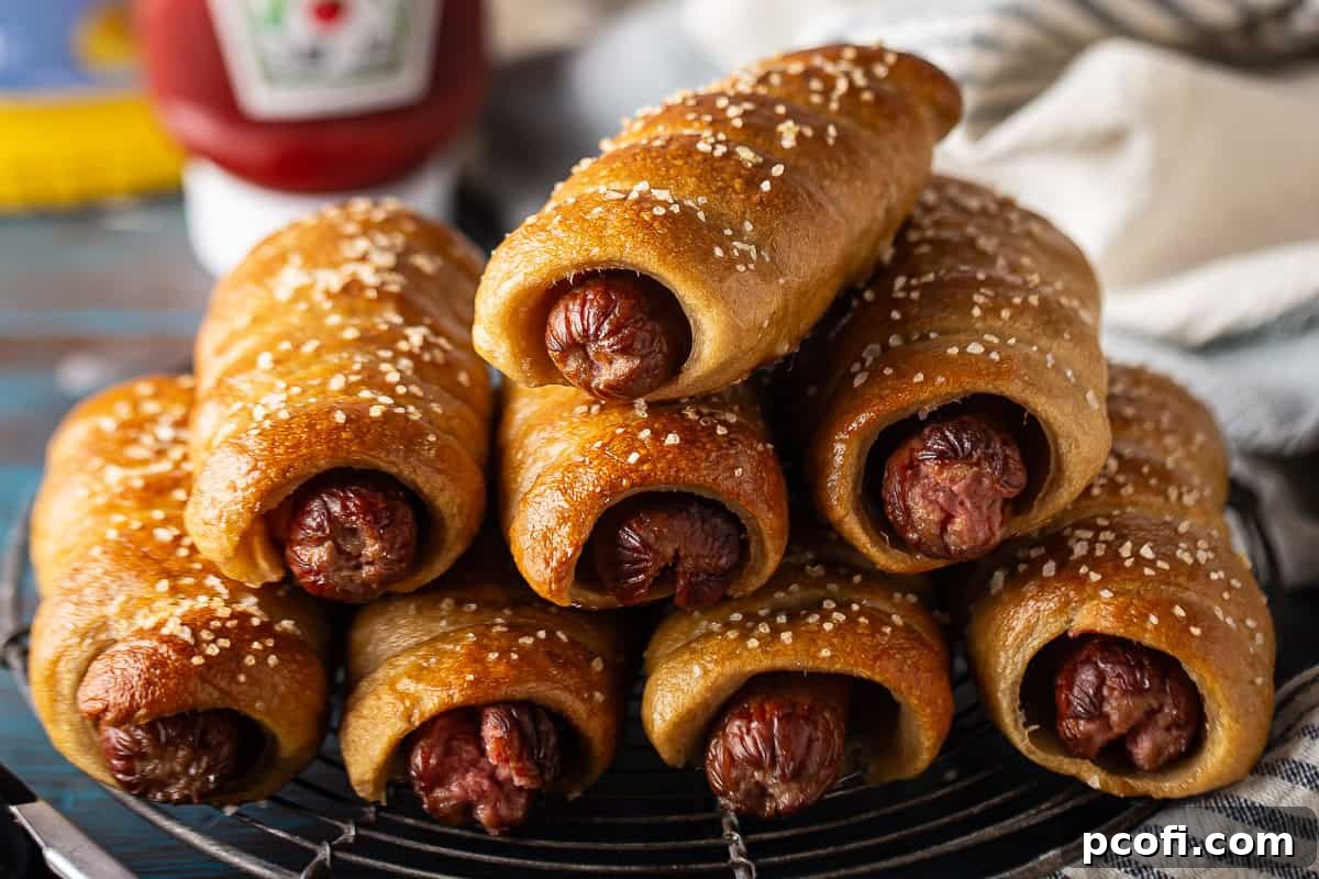 A charming stack of soft pretzel-wrapped hot dogs on a distressed blue background, highlighting their rustic appeal and delicious texture.