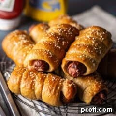 A batch of pretzel dogs stacked on a wire cooling rack.