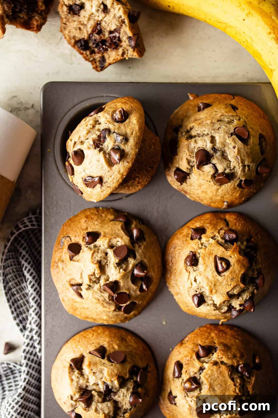 Overhead shot of freshly baked banana chocolate chip muffins cooling in a metal muffin pan.