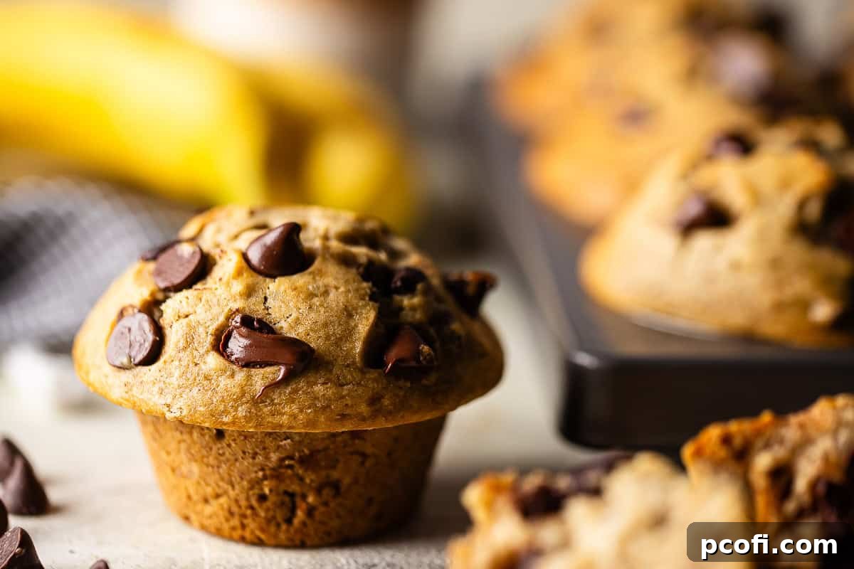Close-up of golden banana muffins with chocolate chips, showcasing their perfectly domed tops and soft texture.