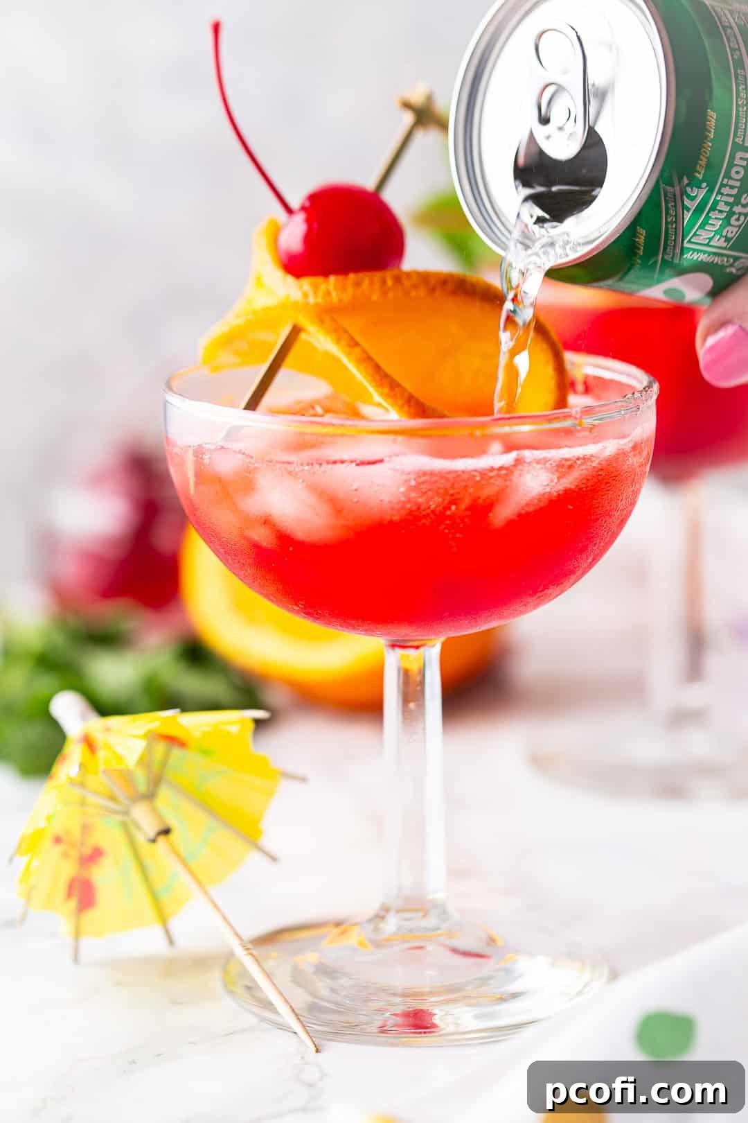 A close-up shot of soda being carefully poured over grenadine and ice, showcasing the beautiful layering process of a Shirley Temple.