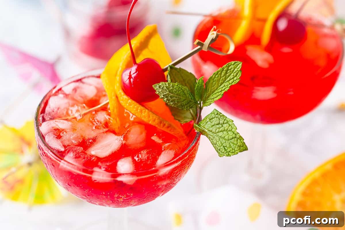 An overhead view looking down into a coupe glass filled with a perfectly prepared Shirley Temple drink, showcasing its inviting color and garnishes.