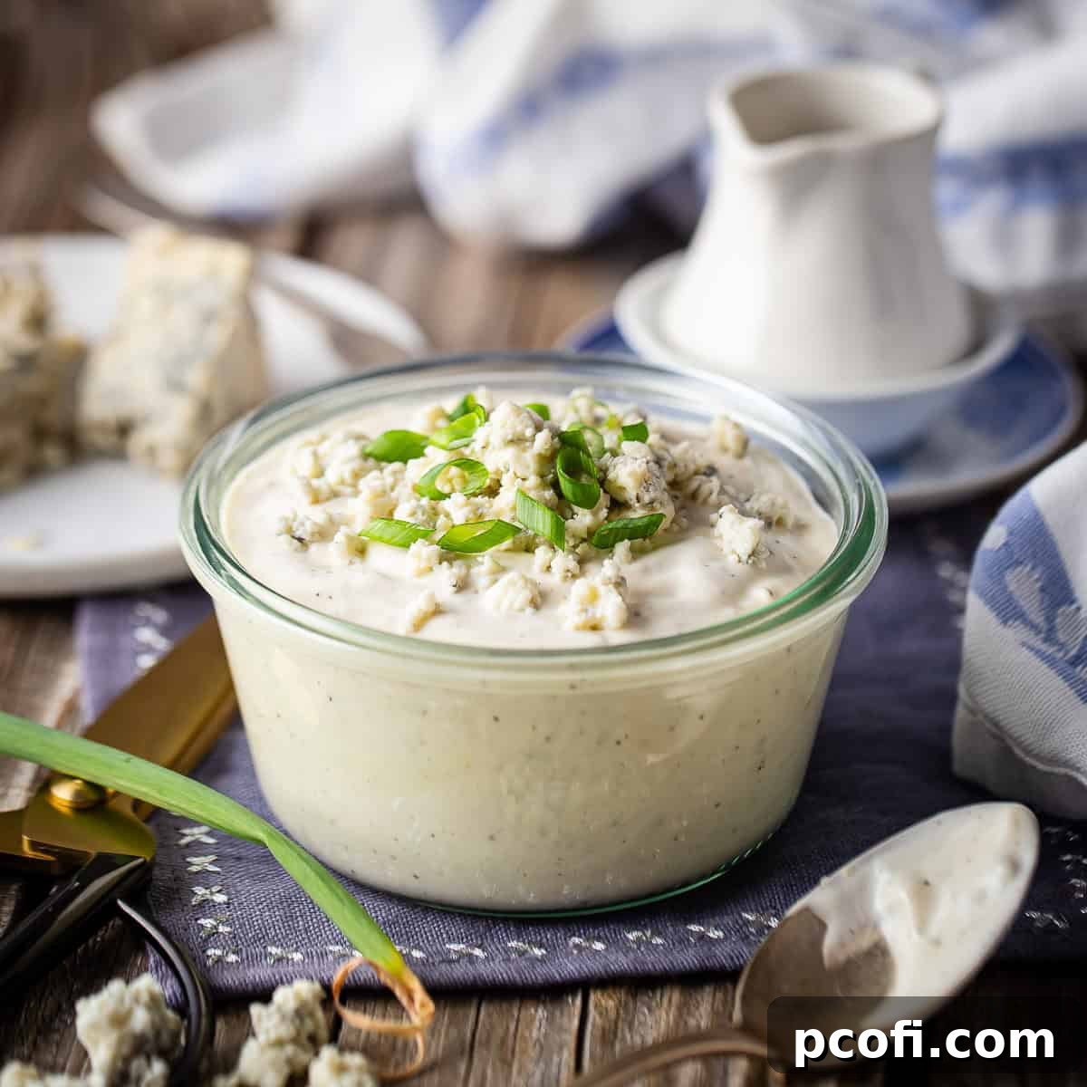 Homemade blue cheese dressing, thick and creamy, served in a clear glass dish and garnished with freshly sliced scallions.