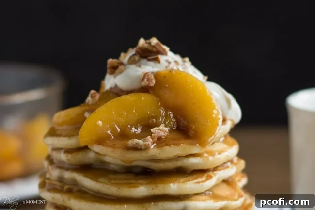 A stack of golden toasted pecan pancakes, generously drizzled with a rich brown butter bourbon peach syrup, a perfect indulgent breakfast.