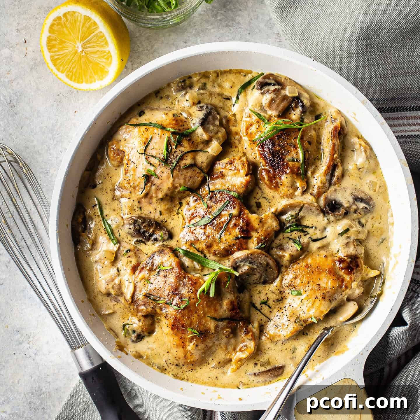 Overhead image of chicken Dijon in a white ceramic skillet, garnished with fresh herbs.