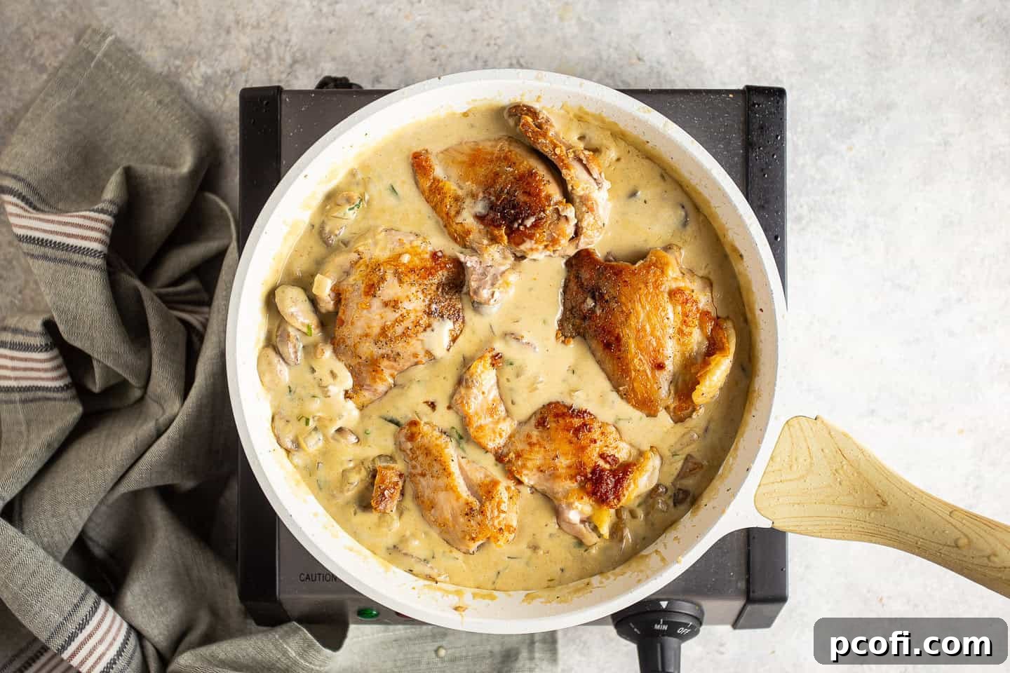 Nestling browned chicken thighs back into the creamy Dijon sauce with mushrooms to finish cooking.