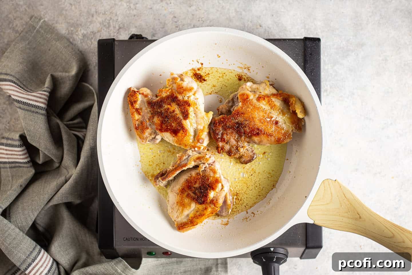 Browning chicken thighs in extra-virgin olive oil in a skillet, creating a golden crust.