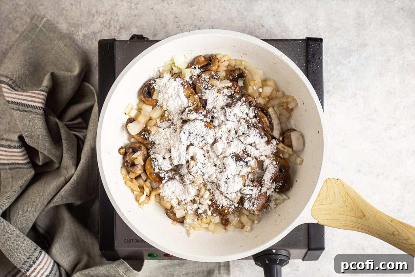 Sprinkling flour over sautéed mushrooms and onions in a skillet to create a roux.