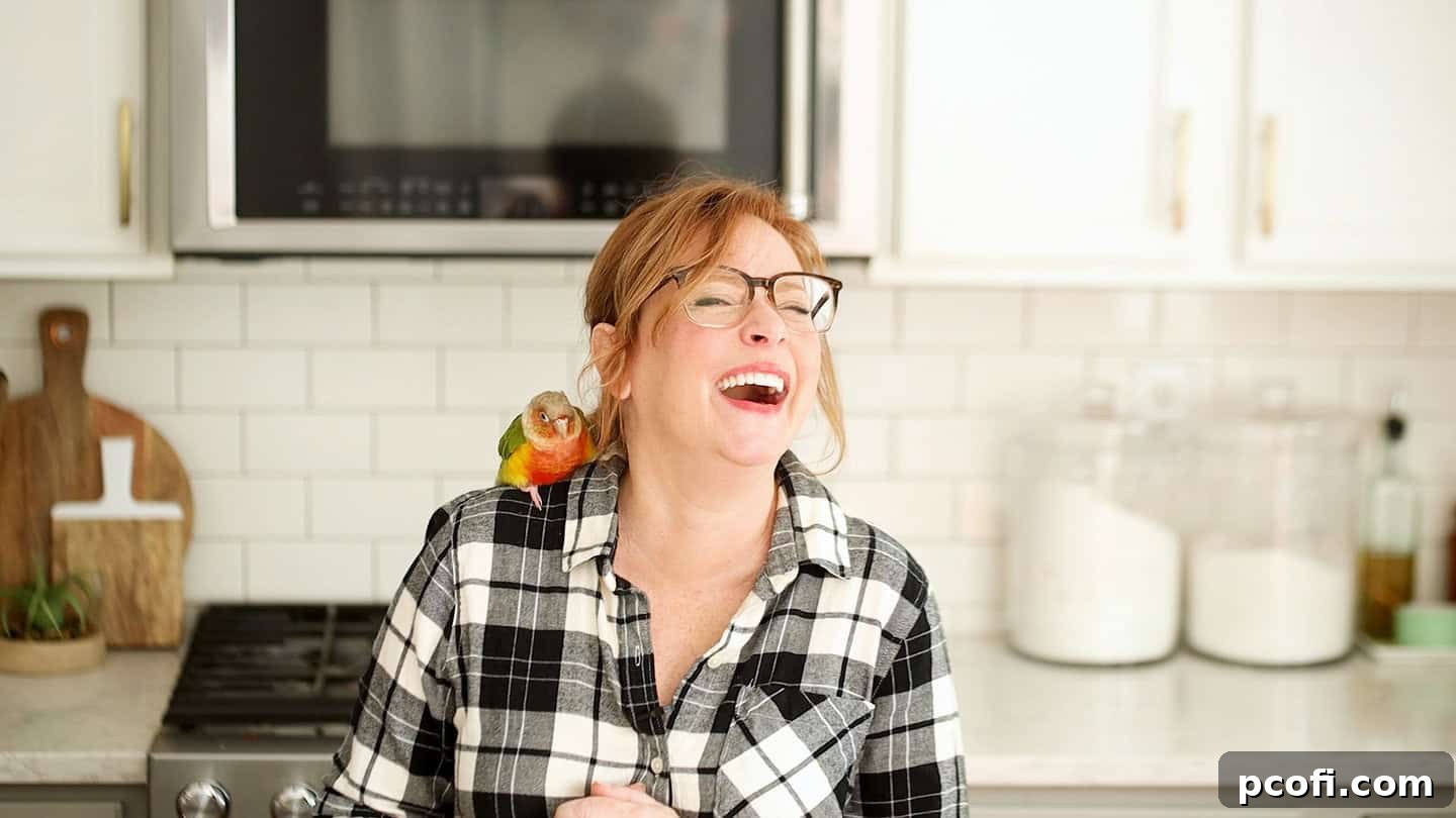 Allie from Baking a Moment laughing joyfully with Bertie perched on her shoulder, embodying newfound happiness and companionship.