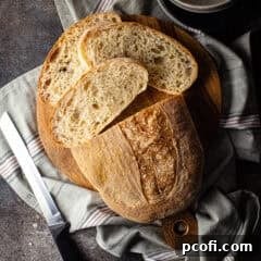 Partially sliced loaf of pan de cristal on a wooden board.