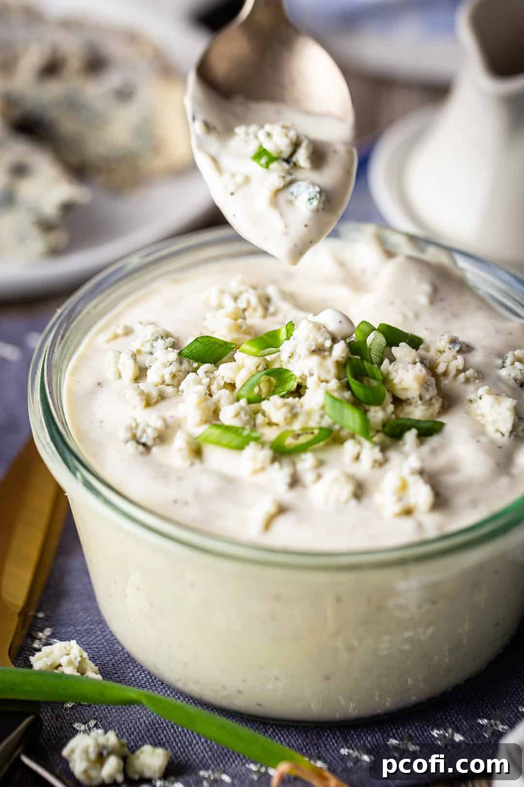 Spooning homemade blue cheese dressing from a green glass bowl.