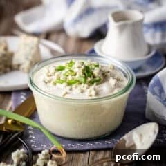 Homemade blue cheese dressing recipe, prepared and presented in a glass dish with sliced scallions on top.