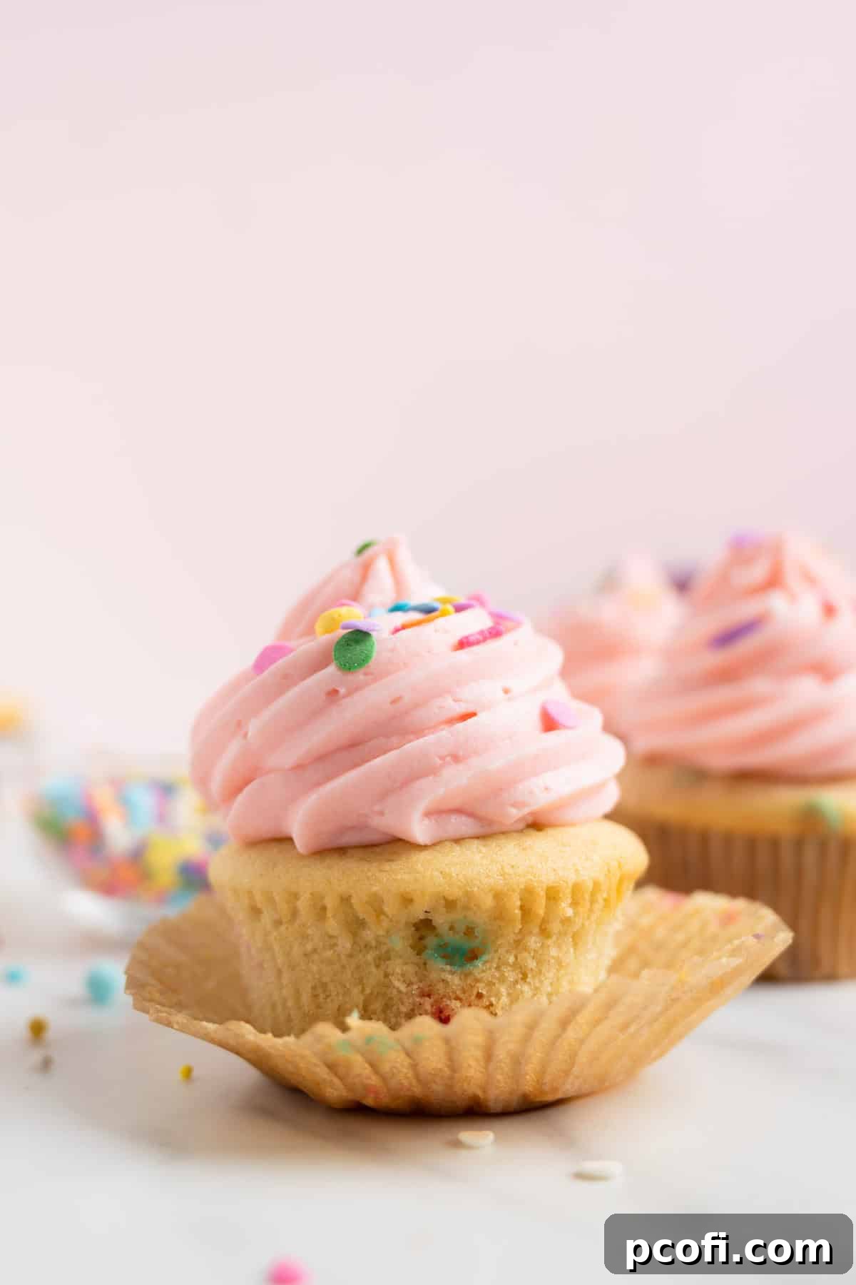 vanilla buttercream tinted pink on top of funfetti cupcakes.