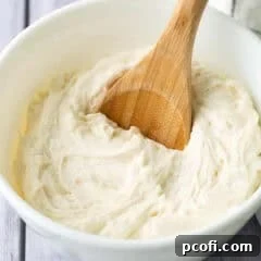 vanilla buttercream frosting in a bowl with a wooden spoon.