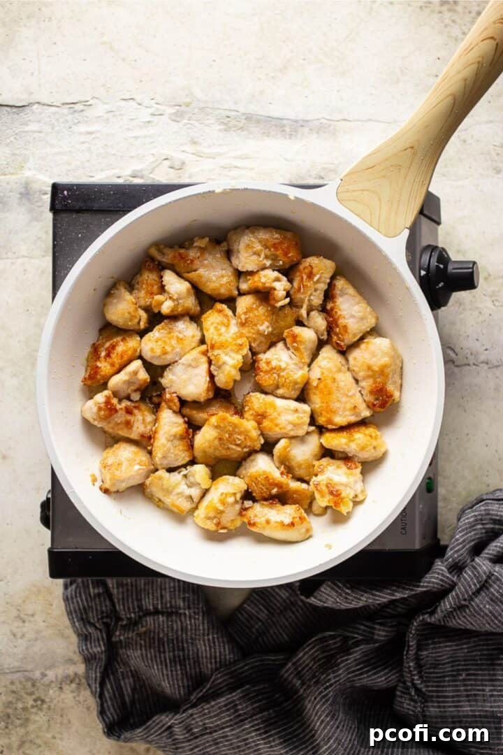 Perfectly browned cubed chicken sizzling in a skillet, showcasing a crispy exterior.