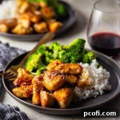 Honey butter chicken topped with sesame seeds on a plate, ready to be enjoyed with a fork.