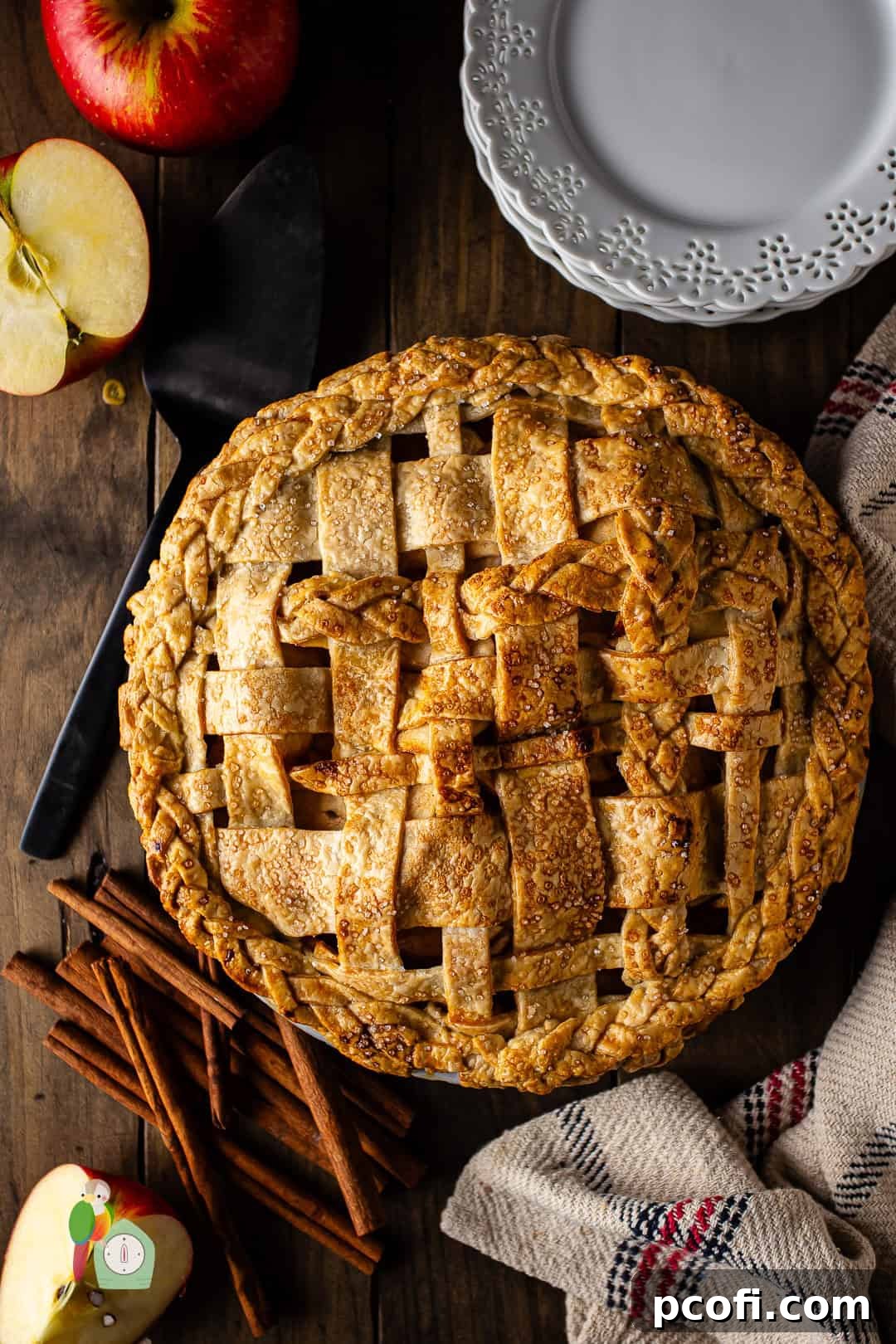 A beautifully crafted apple pie with an intricate lattice crust, resting on a white surface.