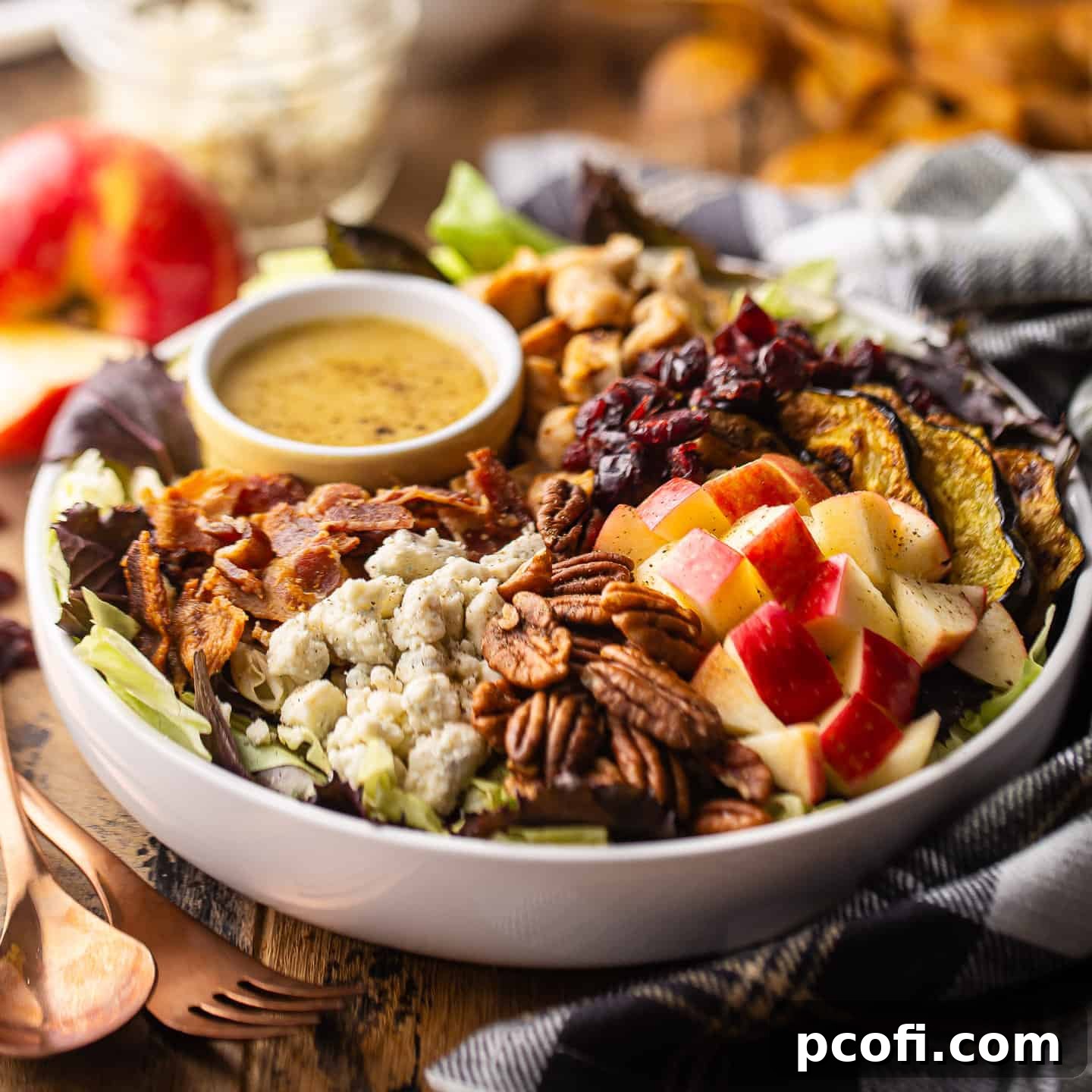 A vibrant fall salad served in a shallow white bowl, drizzled with maple apple cider vinaigrette.