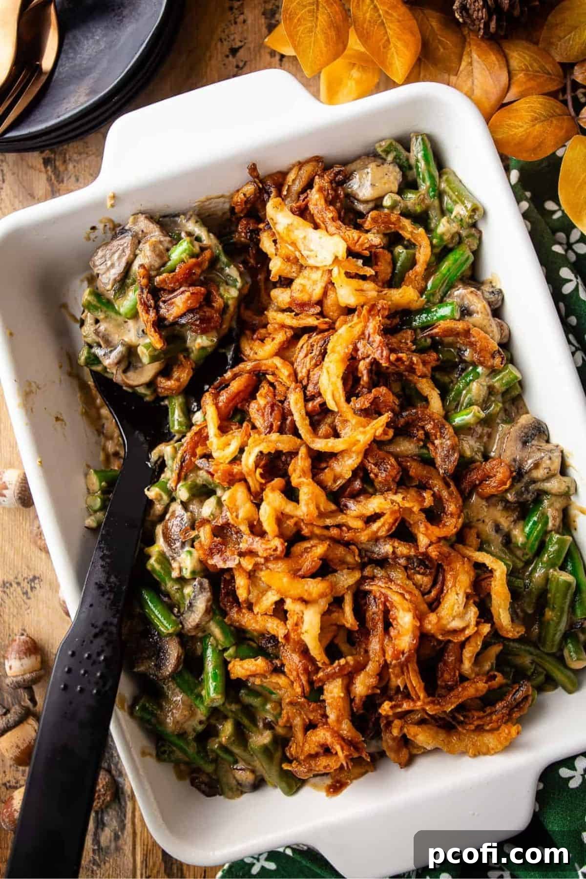 A white baking dish filled with homemade green bean casserole, generously topped with golden fried onions.