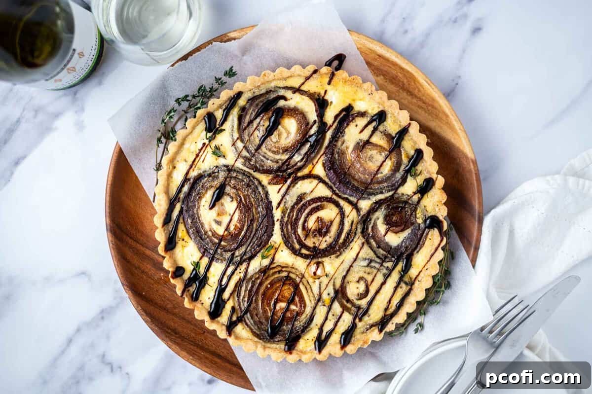 onion tart on a serving tray with plates and utensils