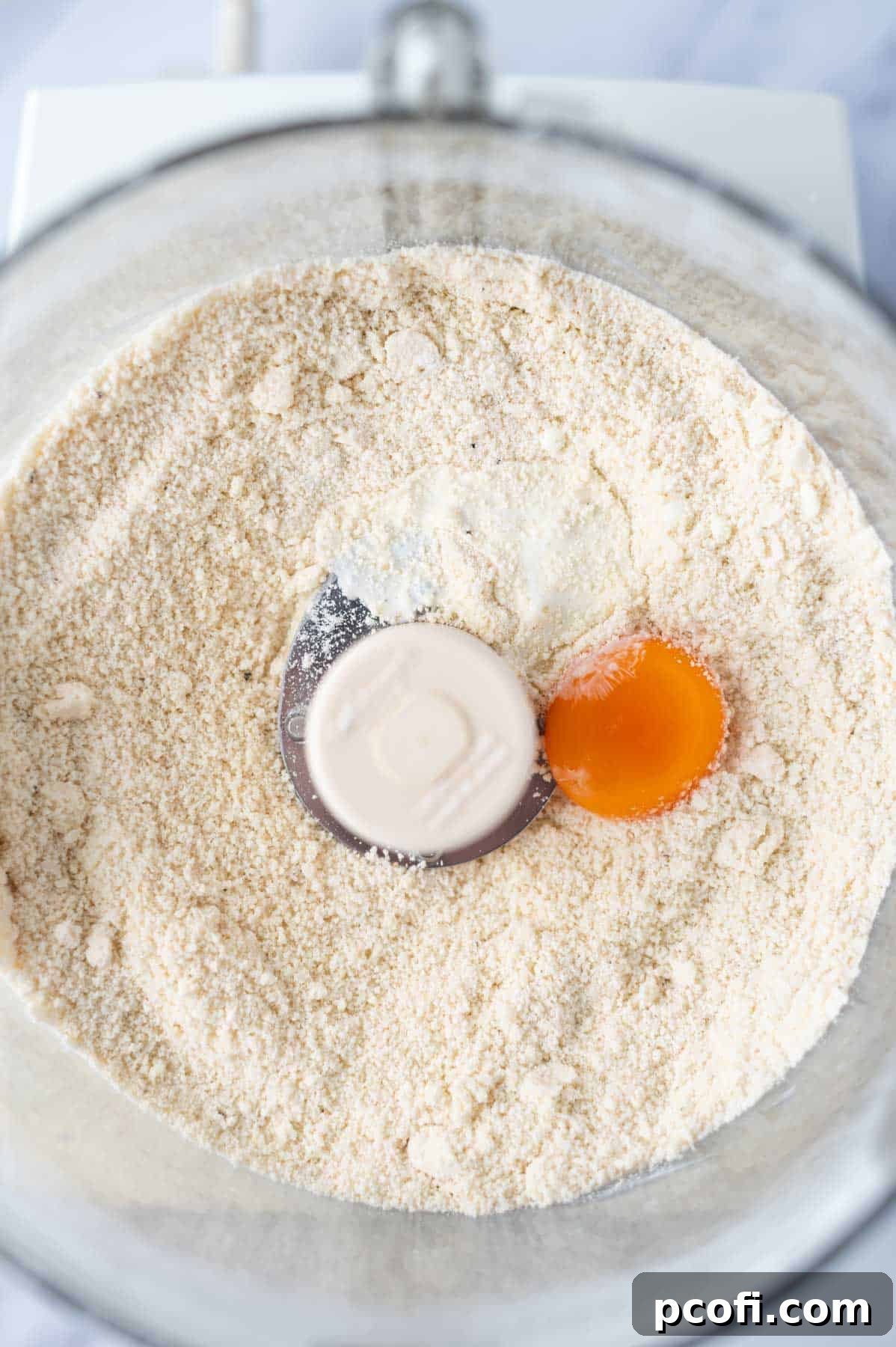 egg yolk and cream added to pastry dough in the bowl of a food processor