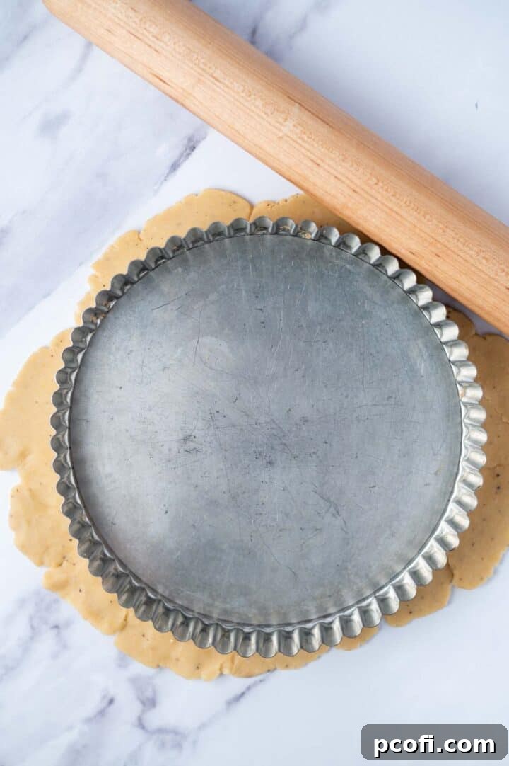 tart pan laying over rolled out pastry dough