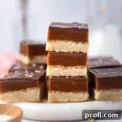 A stack of golden Millionaire Shortbread bars on a serving tray, showcasing their perfect layers.