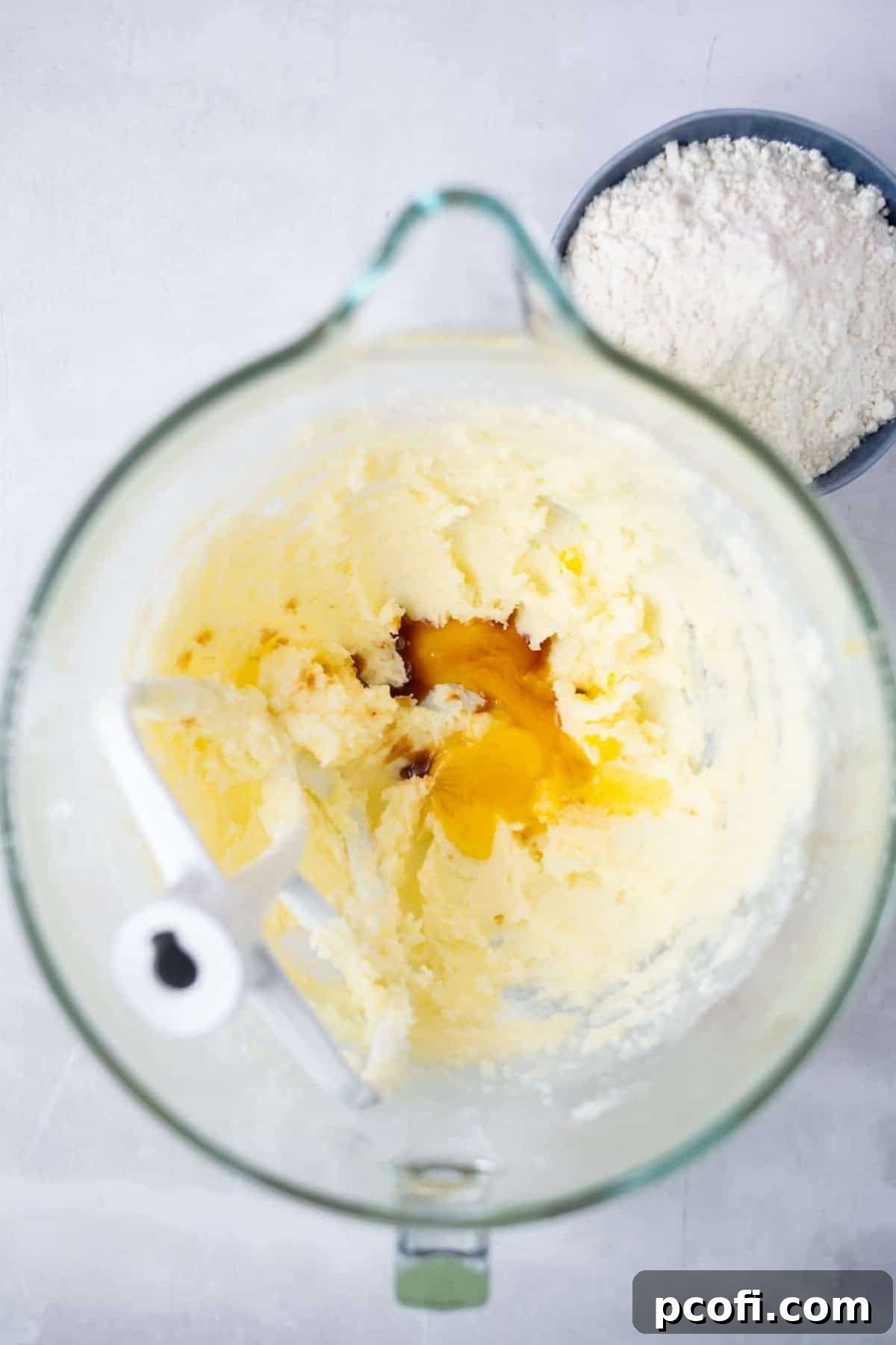 Creamed butter and sugars with an egg yolk and vanilla extract in a mixing bowl, forming the base for the millionaire caramel shortbread recipe.