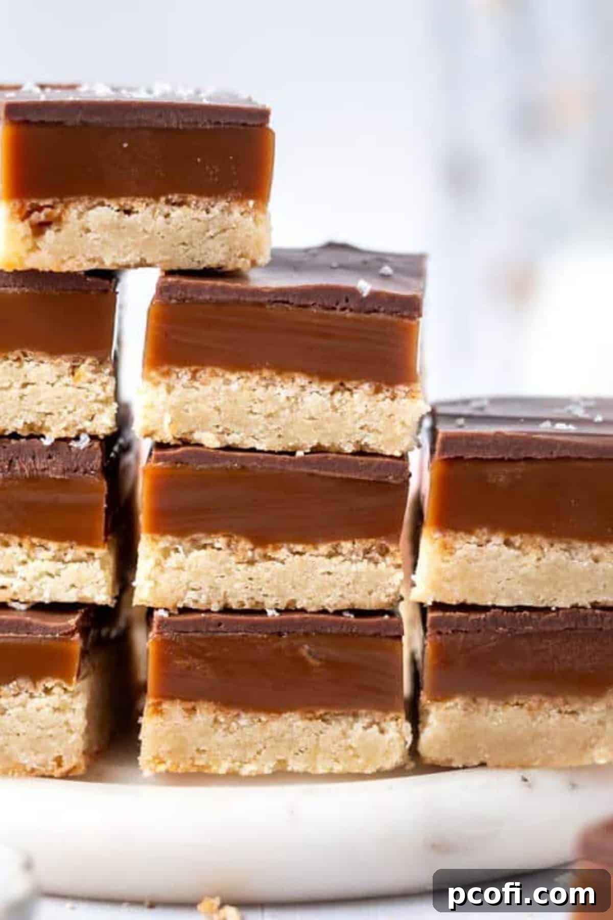 A stack of beautifully cut millionaire's shortbread bars, displaying all three layers, presented on a decorative tray.