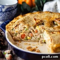 A rustic turkey pot pie in a deep dish, with a golden-brown, flaky crust.