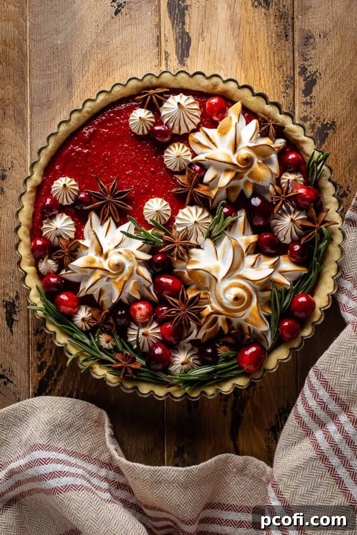 meringue stars and sugared cranberries adorn a vibrant cranberry tart, ready for holiday serving.