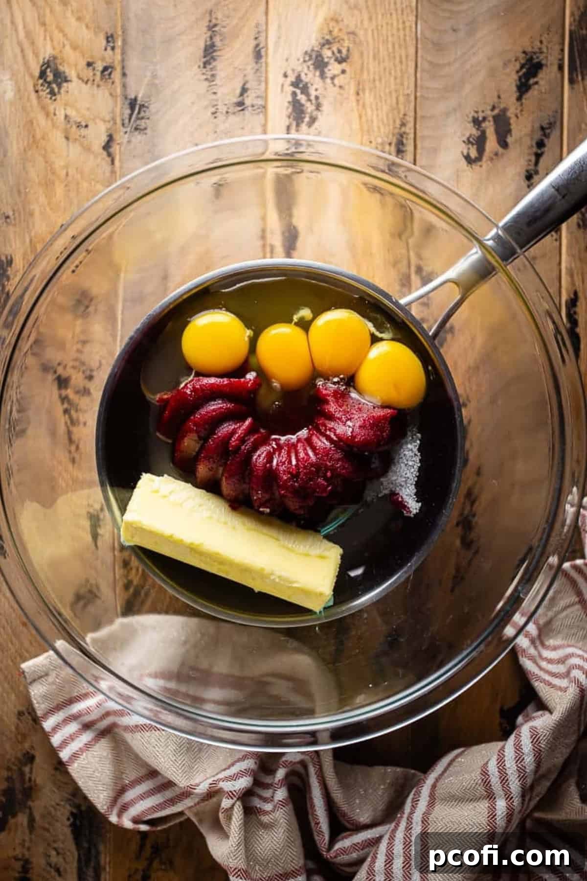 Raw ingredients for the cranberry curd filling, including eggs, cranberry sauce, and butter, prepared in a glass bowl.
