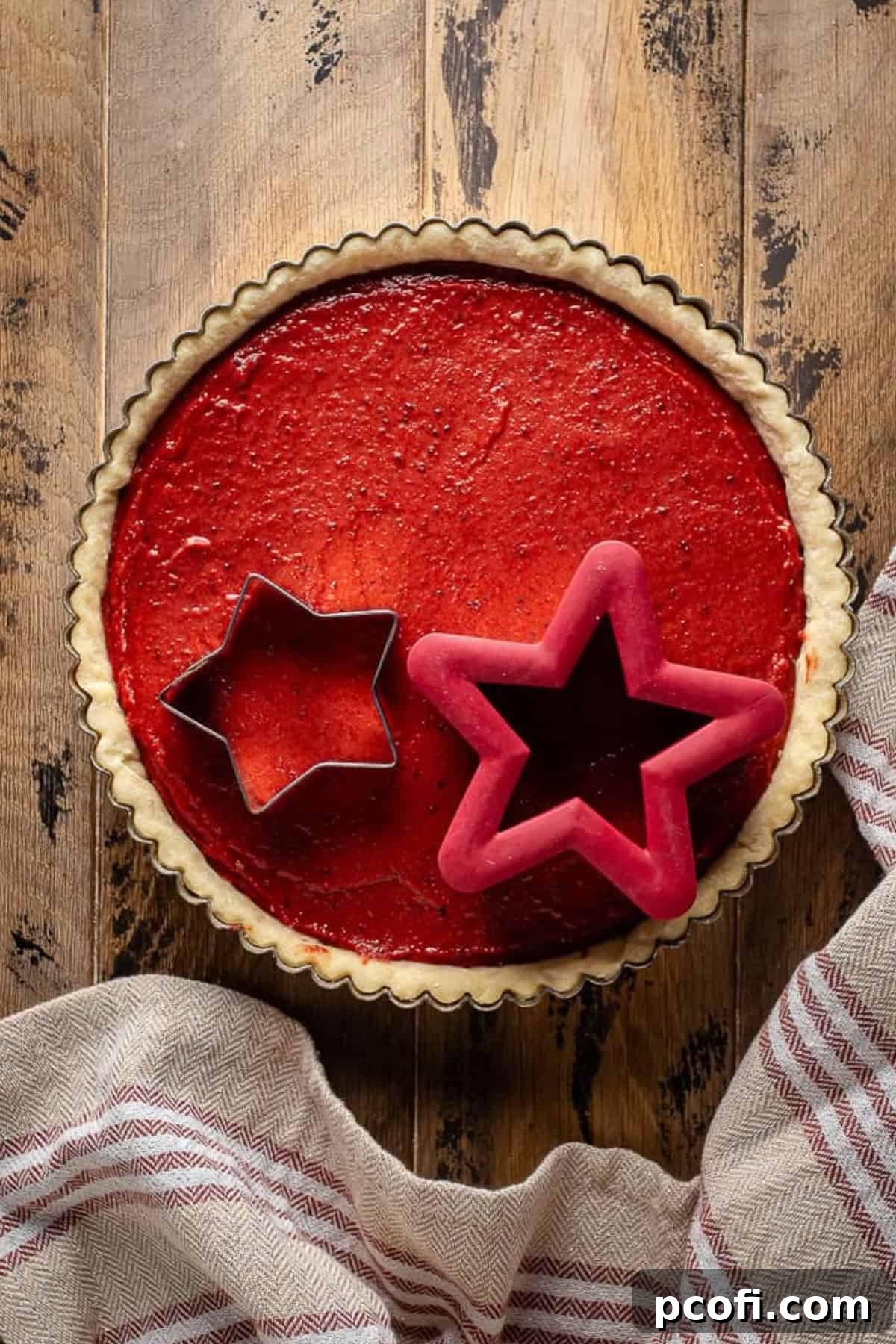 A vibrant cranberry curd filling is poured into a golden par-baked shortbread crust within a tart pan, ready for the oven.