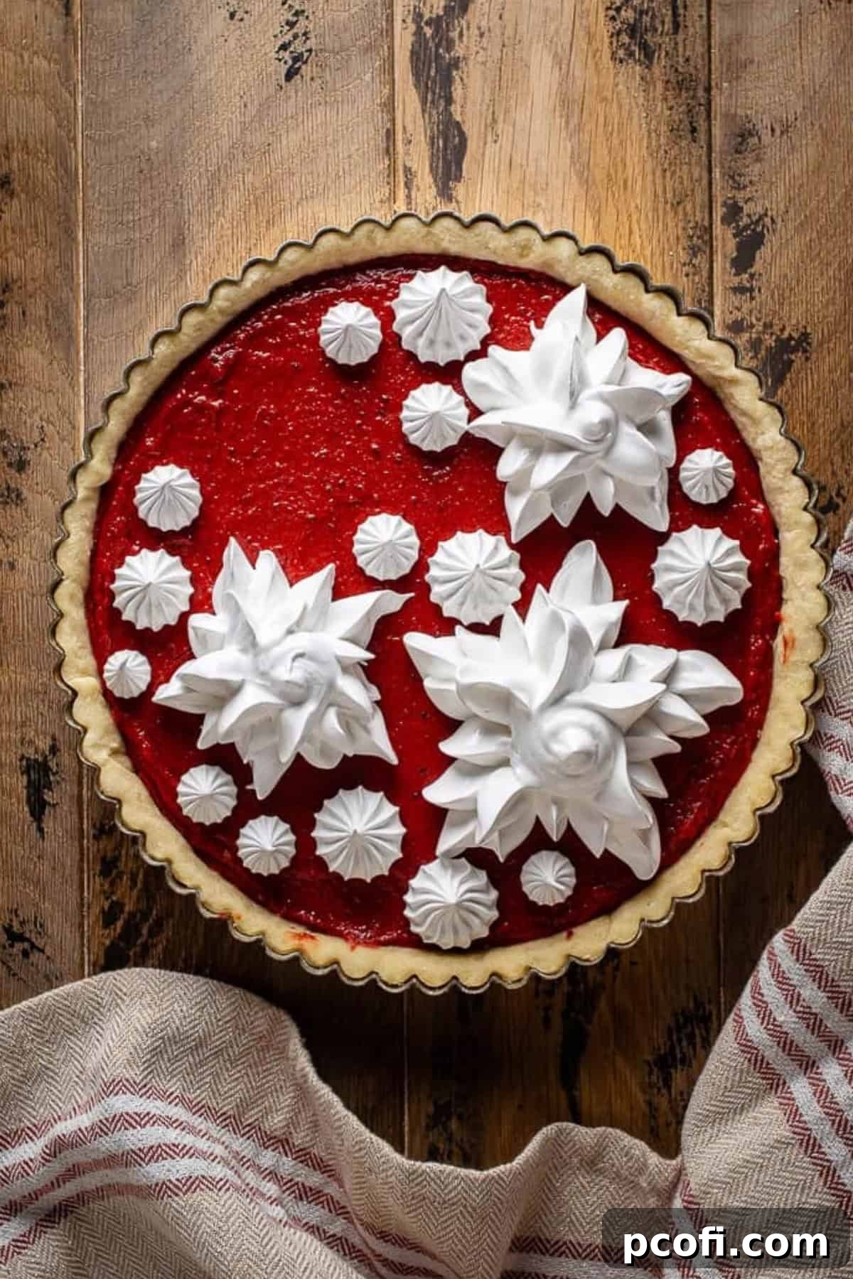Meringue stars delicately piped onto a cooled cranberry curd tart, showcasing a festive and elegant presentation.