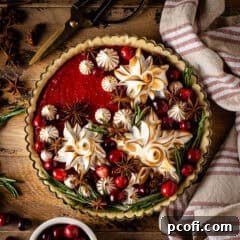 A vibrant Cranberry Curd Tart adorned with fluffy meringue and fresh cranberries, presented beautifully for holiday enjoyment.