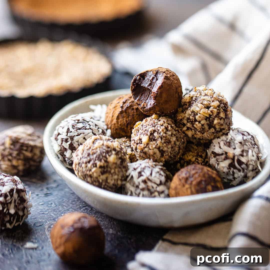 Elegant chocolate truffles artfully stacked in a pottery dish, with festive tins of crushed nuts visible in the soft background.