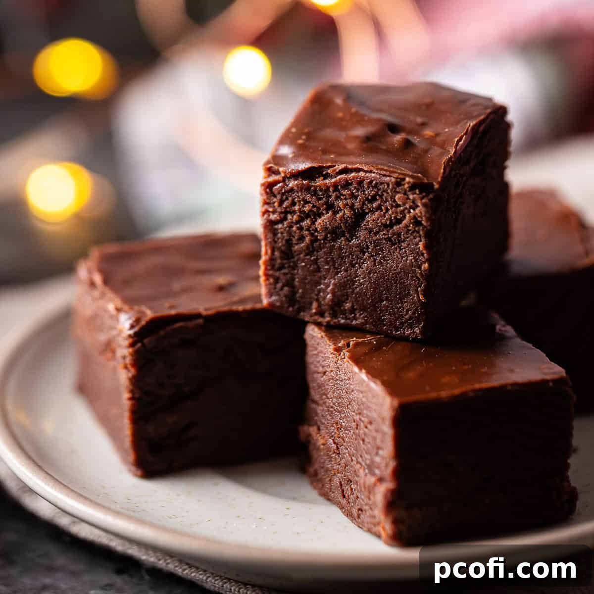 Delicious squares of easy fudge, perfectly stacked on a plate, highlighting its rich and smooth texture, ready to be enjoyed.