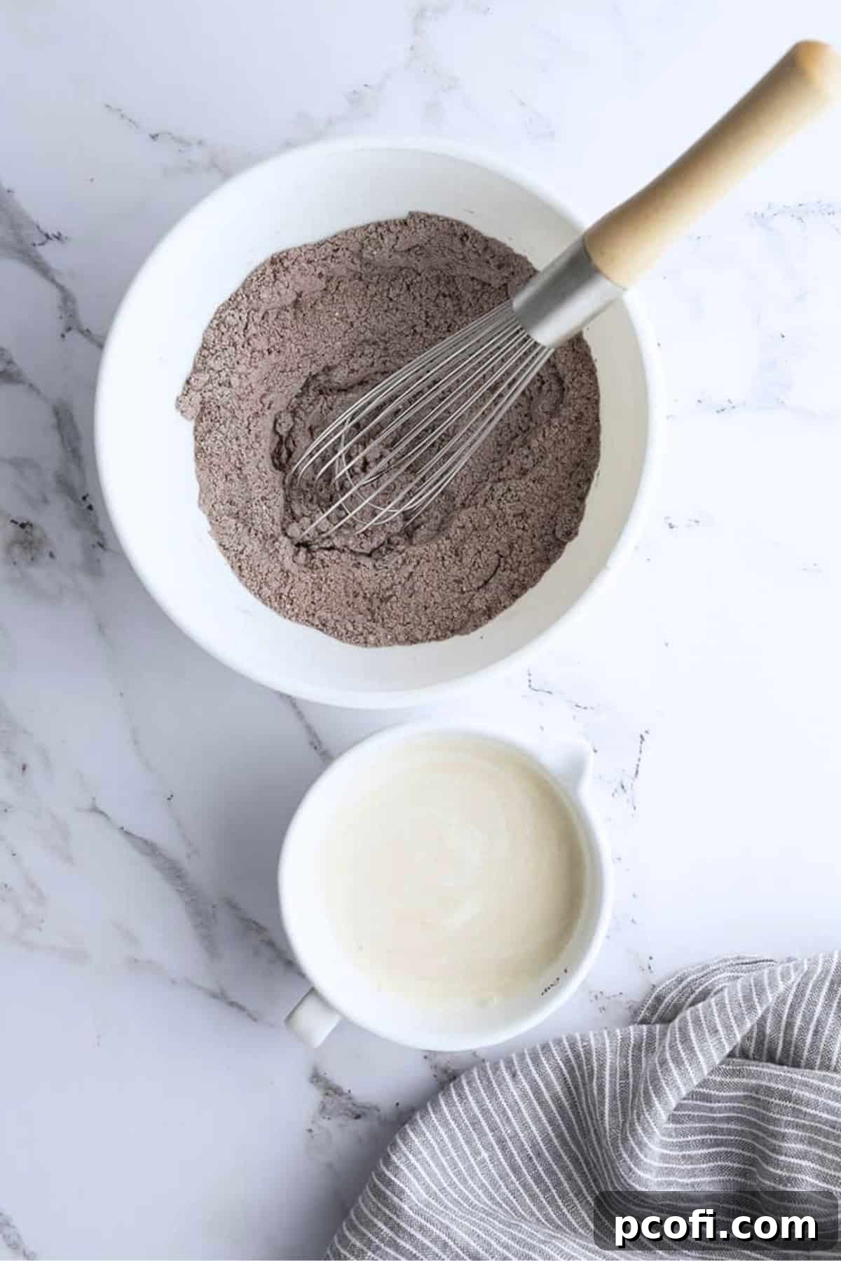 Dry ingredients in a mixing bowl with a whisk, ready to be combined for the cupcake batter.