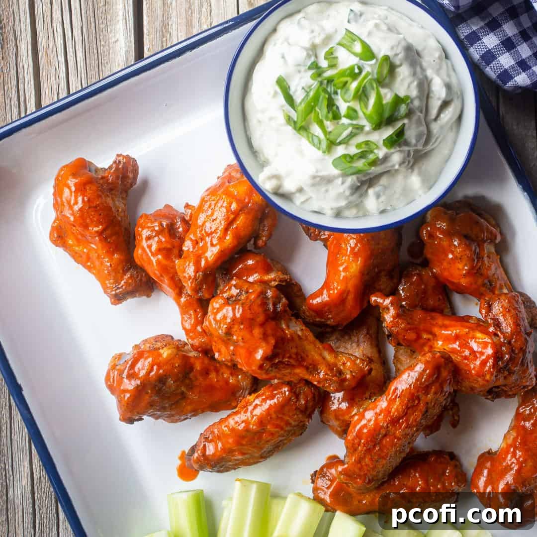 Crispy baked chicken wings coated in a vibrant spicy buffalo sauce, served on a platter with cooling blue cheese dressing and fresh celery sticks.