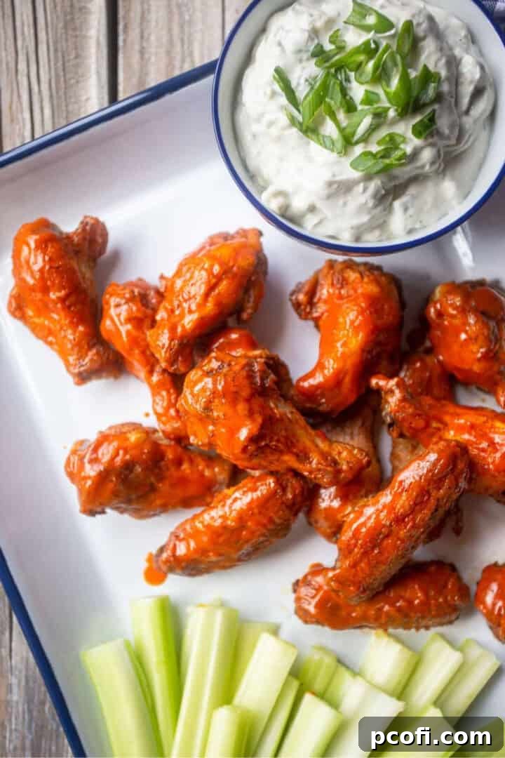 A platter of classic buffalo chicken wings served with a side of blue cheese dressing, garnished with celery sticks.