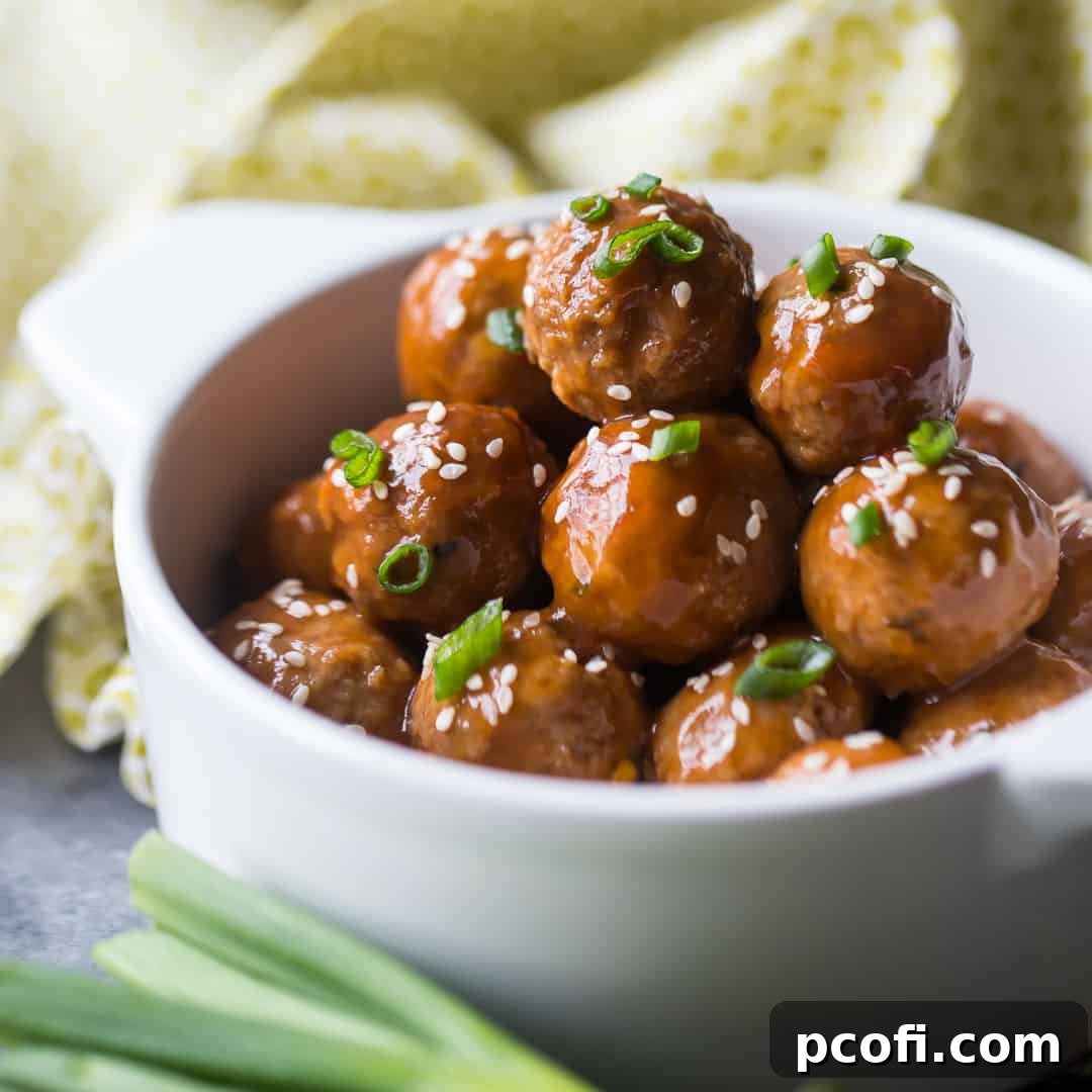 Glazed sweet and sour meatballs, garnished with fresh scallions, simmering deliciously in a white crockpot.