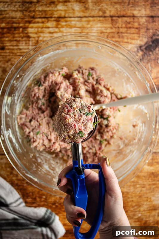 Step 2: A hand uses a 1/4-cup trigger scoop to portion out the meatball mixture.